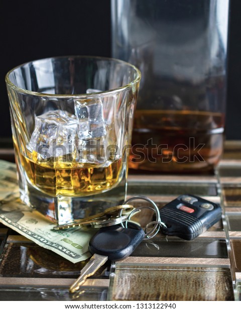 Glass with alcohol\
and ice on tile foreground.  Keys and money next to glass with a\
bottle blurred in the background.  Suggestive of alcoholism and\
drinking and driving.