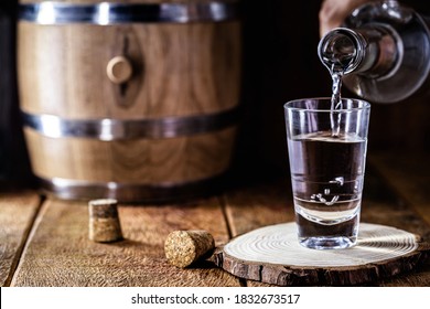 glass of alcoholic drink with bottle, hand filling glass. Image of bar, pug, spirits of the type Aguardente, such as tequila, rum, vodka or cachaça
