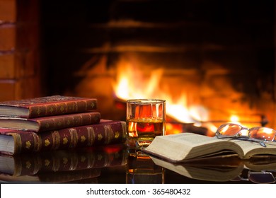 Glass of alcoholic drink wine and antique books in front of warm fireplace. Magical relaxed cozy atmosphere near  fire - Powered by Shutterstock