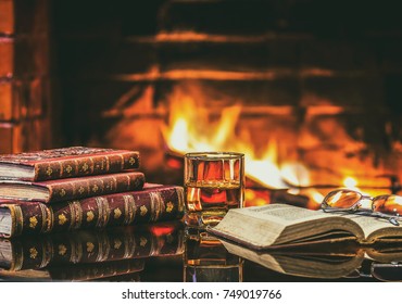 Glass of alcoholic drink wine and antique books in front of warm fireplace. Magical relaxed cozy atmosphere near  fire - Powered by Shutterstock