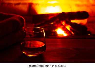 Glass of alcoholic drink wine in front of warm fireplace. Magical relaxed cozy atmosphere near fire
