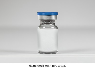 Glass ampoule of vaccine with blank label, isolated on a white background. Vial blue bottle for intramuscular injections. Vaccination, medical concept.
