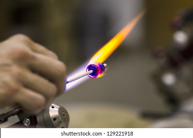 Glass artist using a propane torch to shape colorful glass