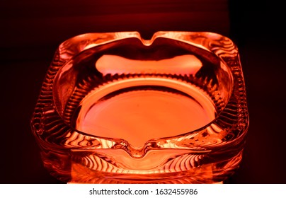 A Glass Ash Tray In Orange Light