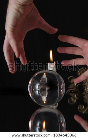 a glass ball on a dark background in which a candle is displayed during a spiritualistic session