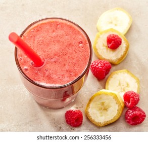 Glass Of Banana And Raspberry Smoothie With A Straw With Fresh Berries For Healthy Dieting Breakfast