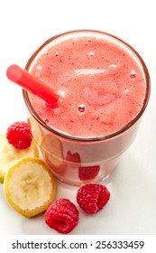 Glass Of Banana And Raspberry Smoothie With A Straw With Fresh Berries For Healthy Breakfast