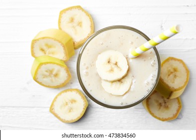 Glass Of Banana Smoothie On White Wooden Background From Top View