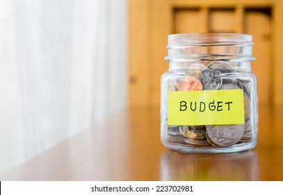 Glass bank with many world coins and budget word or label on saving money jar - Shutterstock ID 223702981