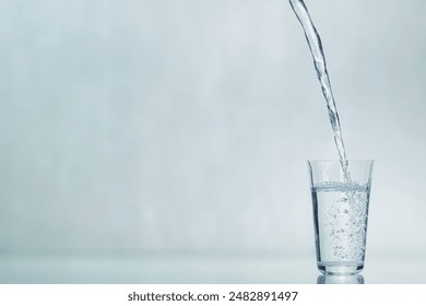 A glass beaker is filled with water. The process of filling a glass with water. Pouring water into a glass on a blue background. Copy space. - Powered by Shutterstock