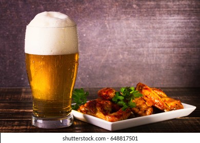 Glass of beer and buffalo chicken wings. Beer bites