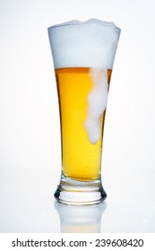 A Glass Of Beer With A Cap Of Foam. With Droplets Of Condensate, With A Cap Of Foam And A Large Drip Foam. On White Background.