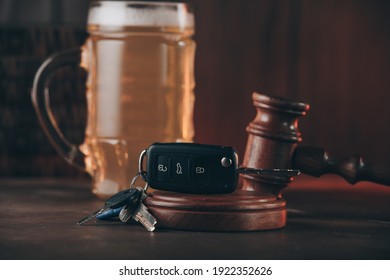 Glass of beer, car keys and judge gavel on a wooden table. Alcohol and car accidents