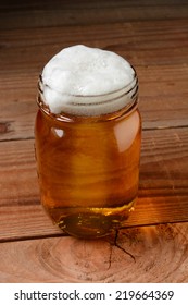 Glass Of Beer In A Country Bar Setting Served In A Canning Jar. Vertical Format On A Rustic Wood Background.