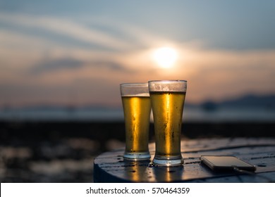 Glass Of Beer On A Beach At Sunset