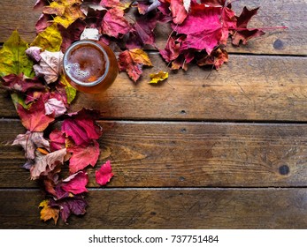 Glass Of Beer Taken From Above With A Scattering Of Fall Leaves On Wooden Background.