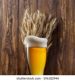 Glass Of Beer With Wheat On Wooden Background