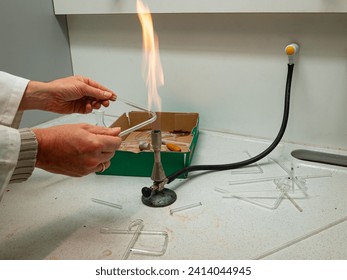 Glass is bent by heating it using a gas burner to make instruments for chemistry