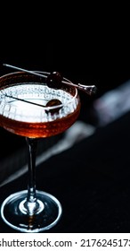 A Glass Of Black Cherry Cocktail On A Black Background