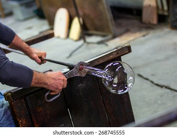 Glass blower at work shaping molten glass, murano venice
