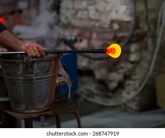 Glass blower at work shaping molten glass, Murano, Venice, Italy
