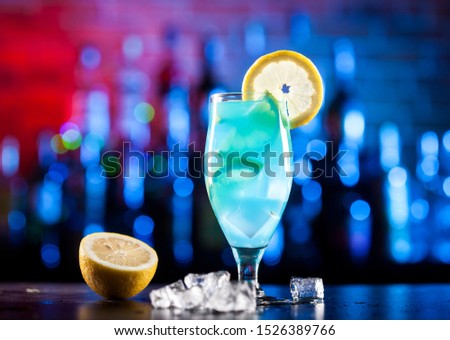 Glass with blue cocktail on bar lights background