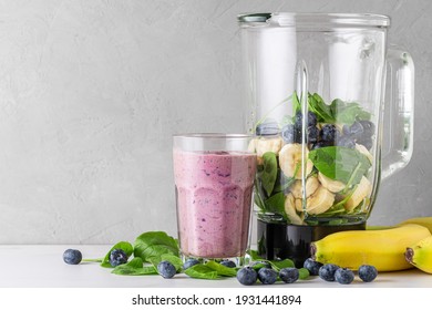 Glass Of Blueberry, Banana And Spinach Smoothie With Fresh Juicy Ingredients In Blender For Making Healthy Drink. Vegan Drink