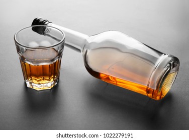 Glass and bottle of alcohol on grey background