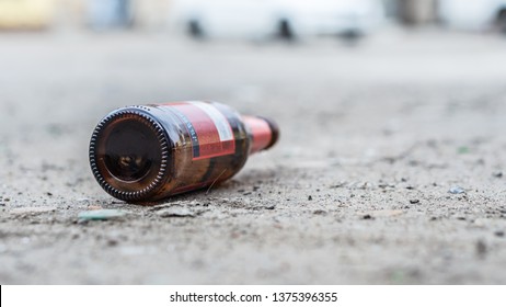 A glass bottle of beer littering on the street - Shutterstock ID 1375396355
