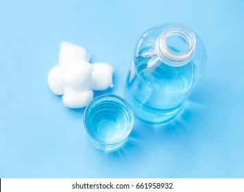 Glass Bottle Of Blue Alcohol And Cotton Wools On Blue Background For Cleaning Injured, Health Care And Medical Concept, Selective Focus