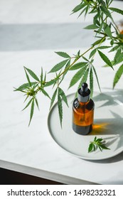 Glass bottle with cannabis oil with hemp leaves on a marble background. Copy space.