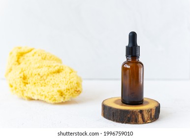 Glass Bottle For Care Oils Or Serums With A Sea Sponge On A Light Background. Concept For A Natural Summer Face And Body Care.