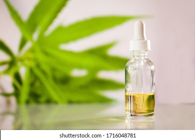 Glass bottle with cbd oil on white background with marihuana leaf