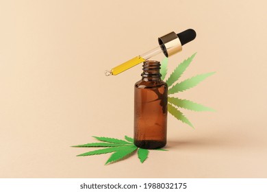 Glass Bottle Of CBD Oil, THC Tincture Over Brown Background. Cosmetics CBD Oil. Droplet Bottle Of Cannabis Oil Extract.