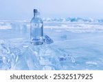 Glass bottle with cold natural drinking water stands on ice of frozen Baikal Lake on winter day. Advertising and branding of drinking fresh ecological water. Nature ice background. Copy space, mock up