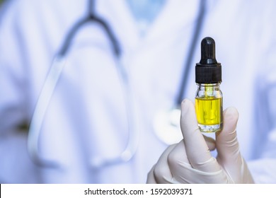 A glass bottle containing CBD hemp oil in the hands of a researcher or medical team. Background with medical stethoscope. Hemp oil, hemp products Medical marijuana for the treatment of diseases
