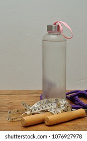 A Glass Bottle Filled With Ice Cold Water, A Measuring Tape And A Jumping Rope