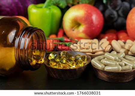 Glass of bottle with food supplement on fruits and vegetables background . Health concept.