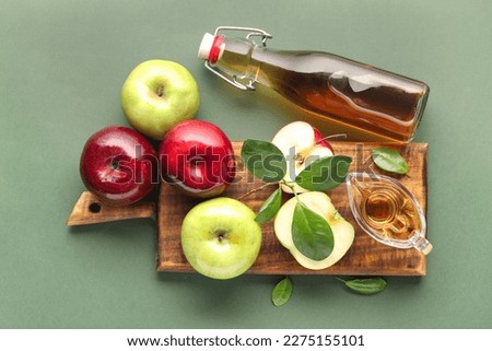Glass bottle of fresh apple cider vinegar and board with fruits on green background Stok fotoğraf © 