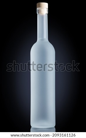 Glass bottle with frost effect on black background. Vodka, gin, or pure water bottle for mock-up.