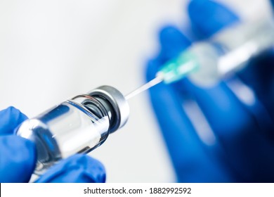 Glass bottle with injection shot,hand in blue gloves holding syringe with needle inserted into ampoule with antiviral liquid,Coronavirus immunization concept,COVID-19 vaccine prevention and protection