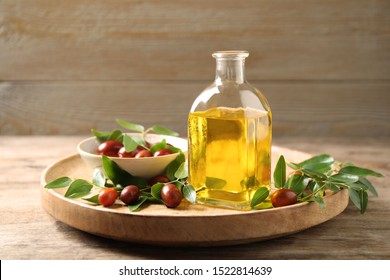 Glass bottle with jojoba oil and seeds on wooden table