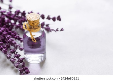 Glass bottle of Lavender essential oil with dried lavender flowers and seeds on white table, aromatherapy spa massage concept. Lavendula oleum - Powered by Shutterstock