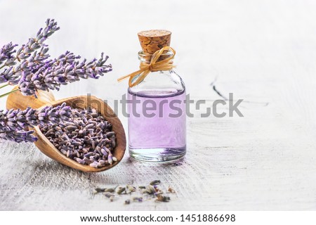 Glass bottle of Lavender essential oil with fresh lavender flowers and dried lavender seeds on white wooden rustic table, aromatherapy spa massage concept. Lavendula oleum Сток-фото © 
