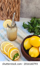 Glass Bottle With Lemon Slush, Lemon Slices, Whole Lemons And Mint