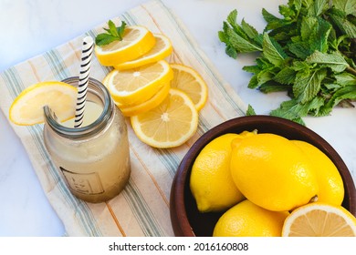 Glass Bottle With Lemon Slush, Lemon Slices, Whole Lemons And Mint