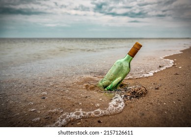 Glass bottle with letter on the beach sand