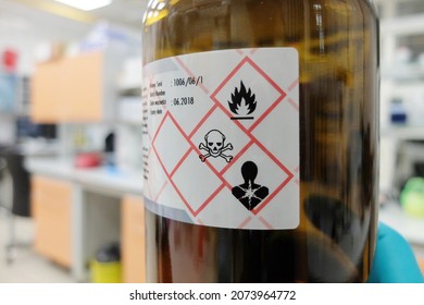 A glass bottle with liquid chemical that is easily flammable, acutely toxic, and poses serious health hazard. Appropriate hazard pictograms are present on the label - Shutterstock ID 2073964772