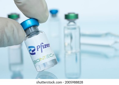 Glass bottle with logo Pfizer and BioNTech in the doctor's hand, American multinational pharmaceutical company. January 18, 2021, Barnaul, Russia.