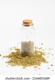 glass bottle with marijuana inside and cork stopper on crushed grass, white background
